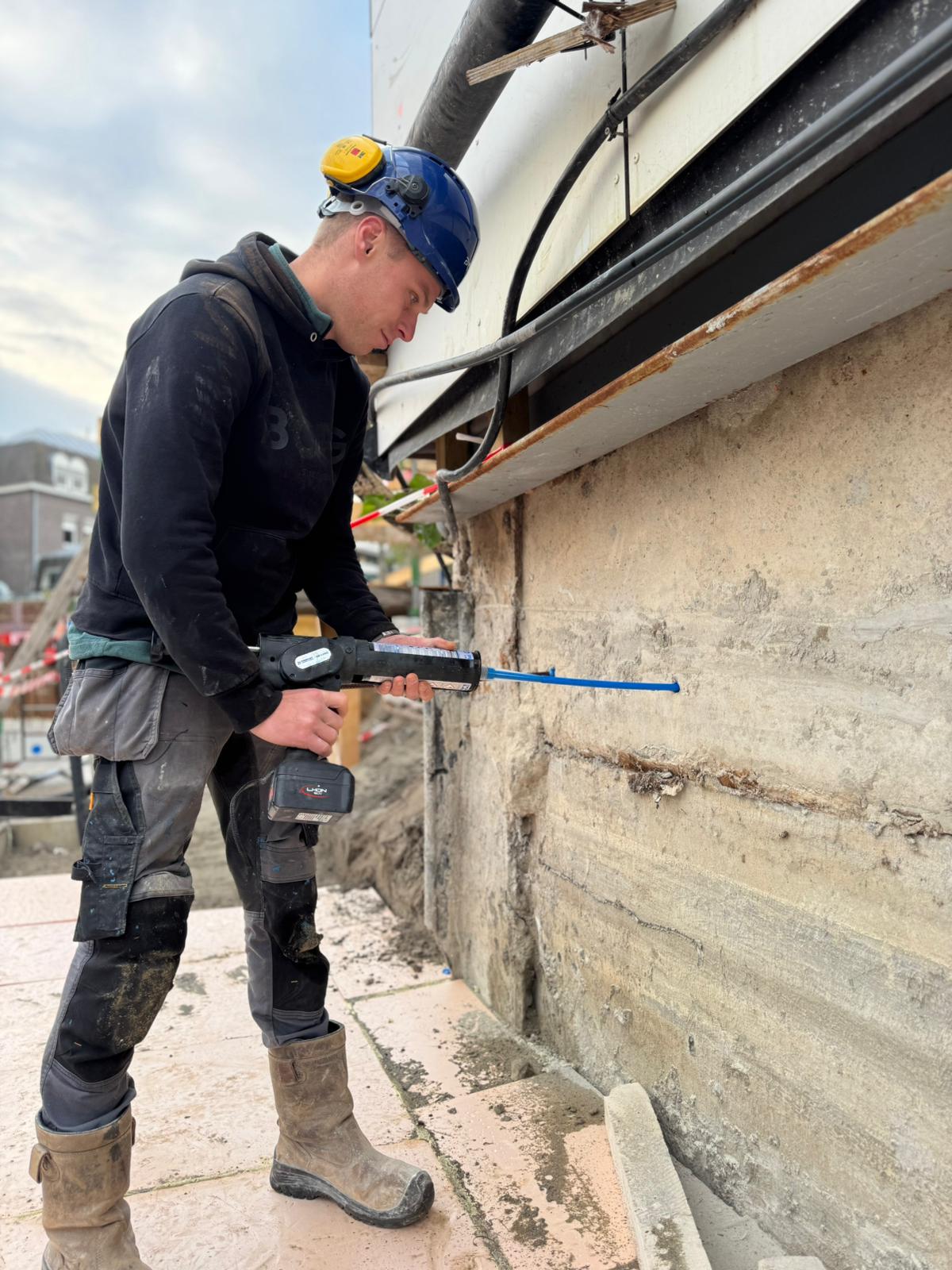 Monteur injecteert chemische mortel in een betonwand